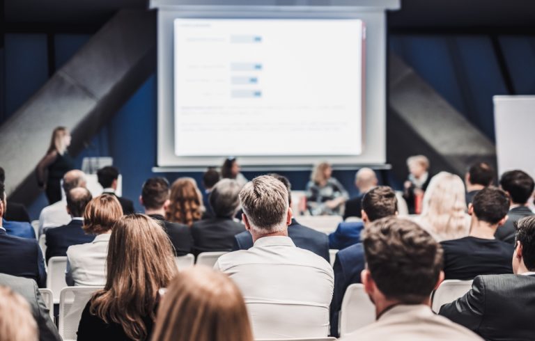 Speaker presenting at a corporate event with the audience carefully listening