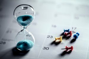 Pushpins and hourglass by a calendar