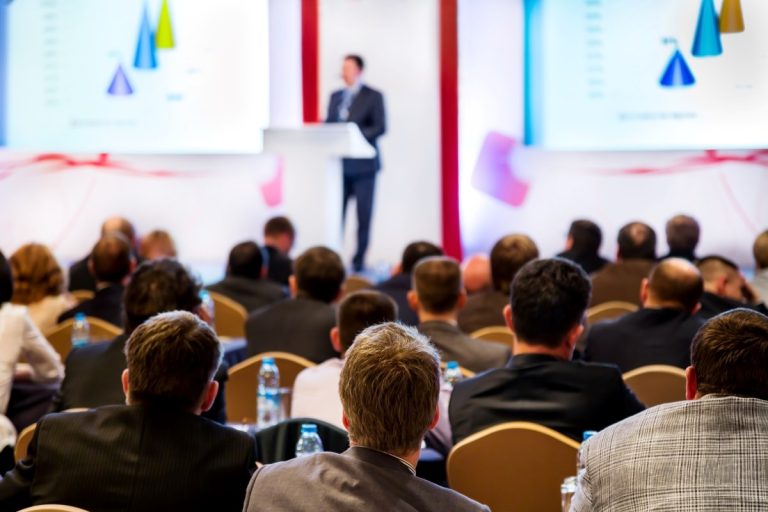 Speaker behind a lectern presenting at a conference