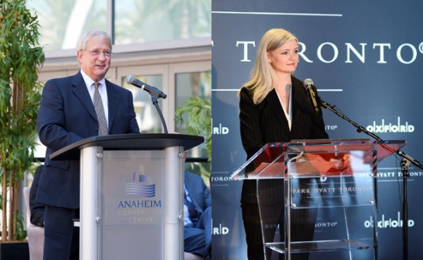 Two individuals at podiums in front of a sign reading "Toronto," engaged in a discussion or presentation.